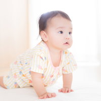 白い服でハイハイをはじめた赤ちゃんの成長記録の写真