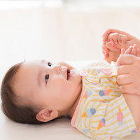 笑顔の赤ちゃんとママの手の写真