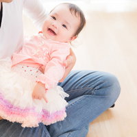 絶賛パパタイム、床に座って赤ちゃんをあやす父親の写真