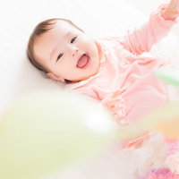 カラフルなベッドメリーを見上げて満面の笑みを浮かべる赤ちゃんの写真