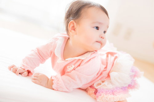 ピンクの服を着てにんまり微笑む赤ちゃんの笑顔