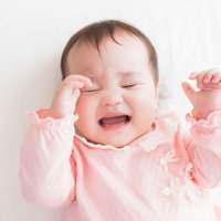 眠たくて仕方がない赤ちゃんが泣く寝ぐずりの様子の写真