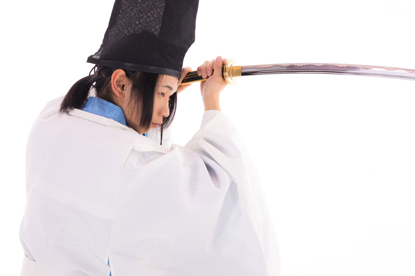 黒い帽子と白い狩衣を着た男性が日本刀を両手で構える［モデル：まーこ］