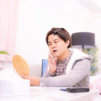 手鏡を持って化粧下地を塗る男性のスキンケアの写真