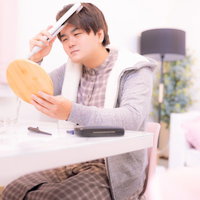 鏡の前で前髪をヘアアイロンでセットする男性の写真