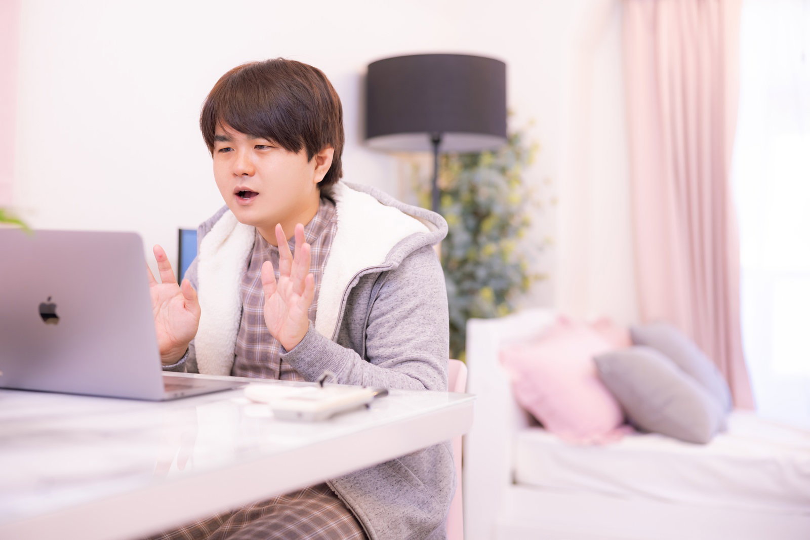 ノートパソコンの画面を見て驚いた表情を浮かべる部屋着姿の男性［モデル：はしも。］