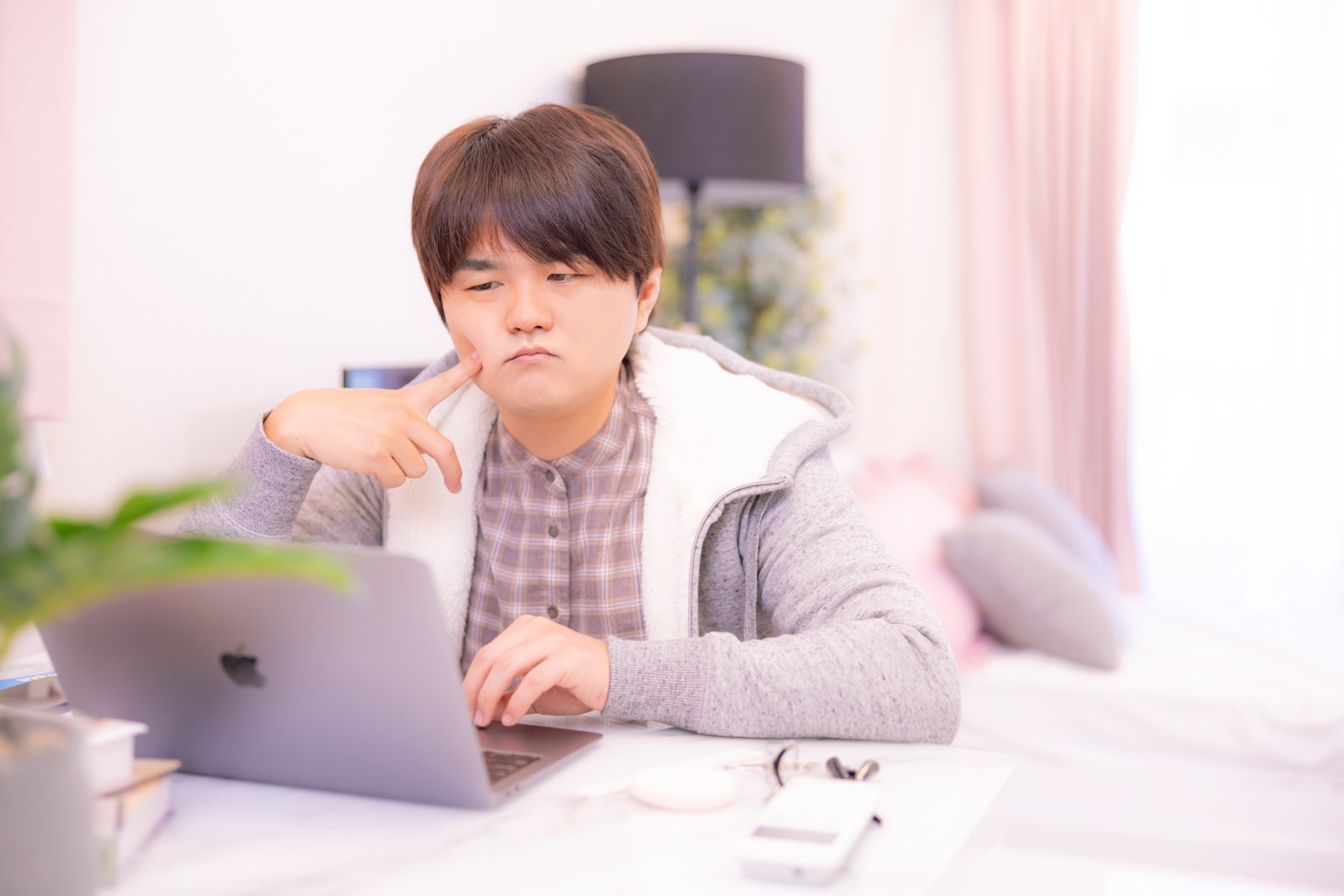 ノートパソコンの前で悩む部屋着姿の男性［モデル：はしも。］
