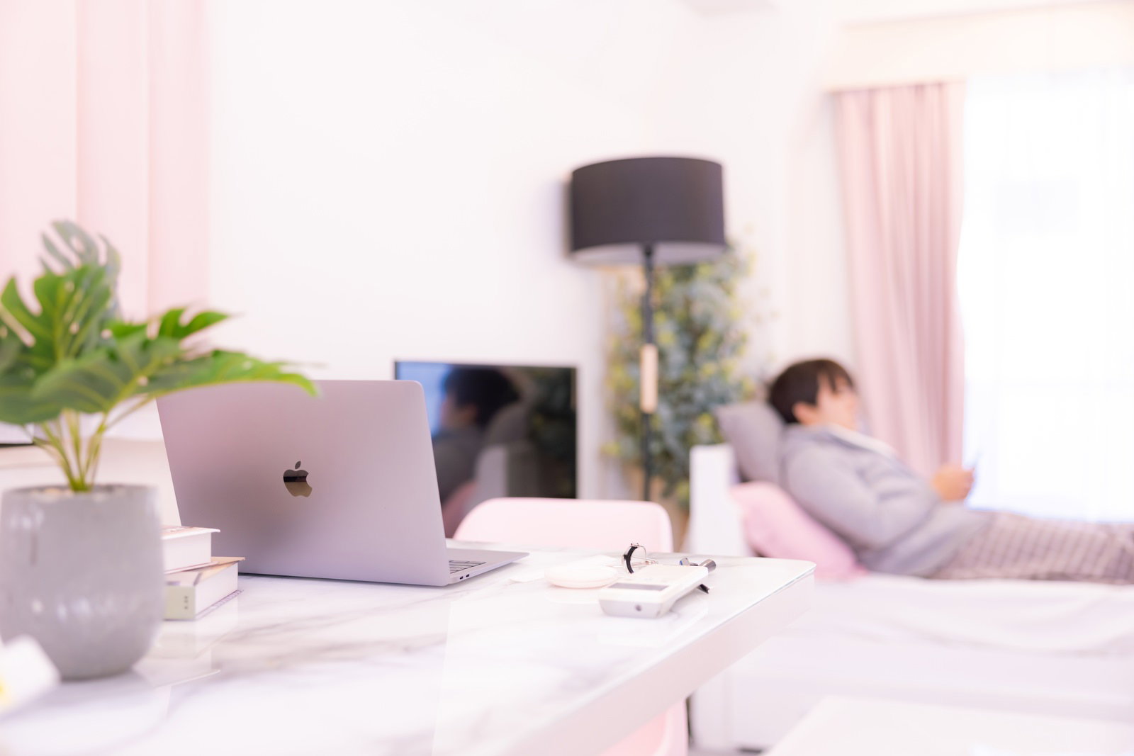 一人暮らしのピンクの部屋でデスクに置かれたノートパソコン［モデル：はしも。］