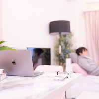 一人暮らしの机の上に置かれたシルバーのノートパソコンの写真