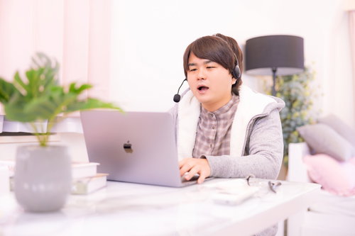 部屋着でヘッドセットをつけてオンライン会議に参加する男性