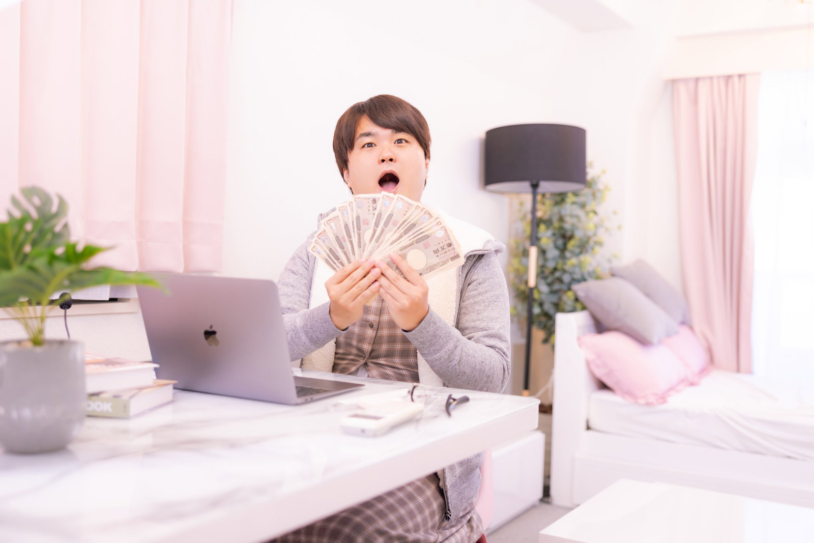 部屋着姿の男性がお札を数えながら配信準備をしている様子［モデル：はしも。］