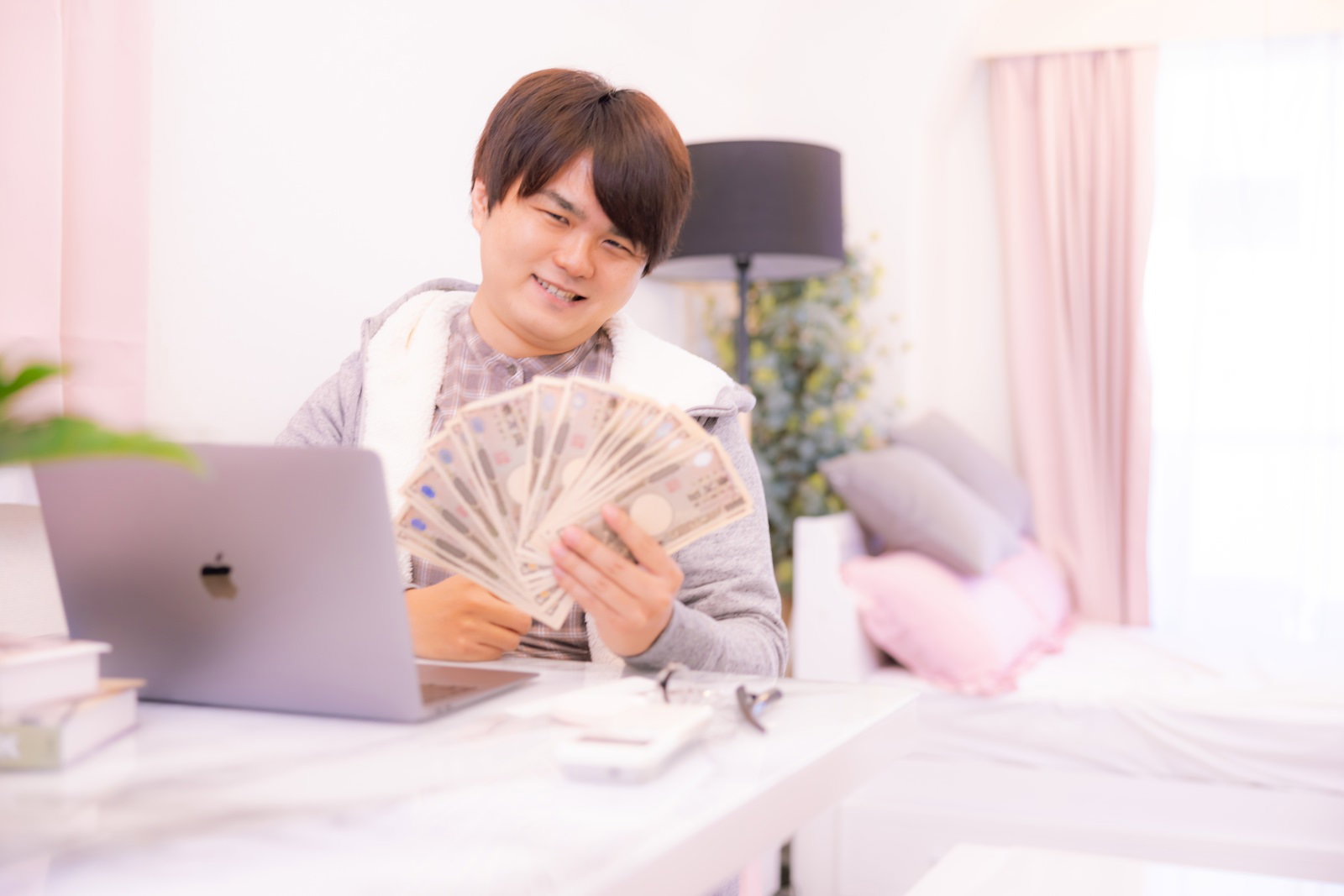 室内で紙幣を扇状に持ちニヤリとする男性［モデル：はしも。］