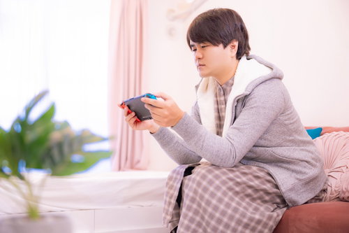 部屋着でゲーム機に真剣に集中する男性の休日風景