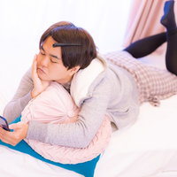 スマホを見ながらベッドでゴロゴロする男性の写真