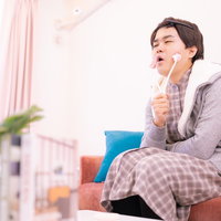 小顔ローラーでセルフケアをする男性の美容ケアの写真