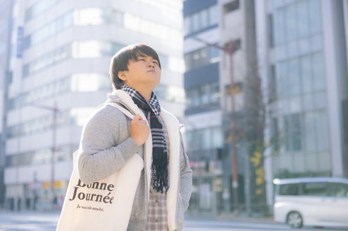 ベージュのコートでトートバッグを持ってお出かけする男性