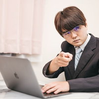 デスクワークをしながらズバリ指摘するビジネスマンの写真