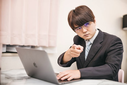 デスクワークをしながらズバリ指摘するビジネスマン