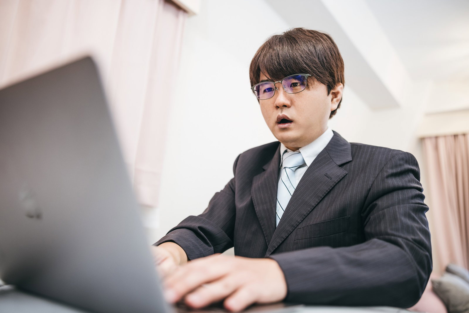 誤爆ツイートに気づいたスーツ姿の男性［モデル：はしも。］