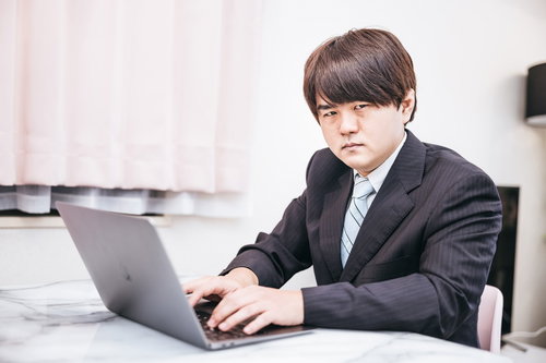 スーツ姿でノートパソコンを使いオンライン会議する男性