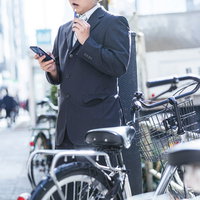 ひとり屋外で愛煙タイム、スーツ姿の男性が電子タバコを吸う休憩シーンの写真