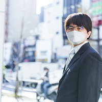 黒いスーツのマスク姿で振り返る会社員の男性の写真