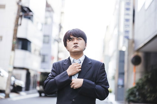 ネクタイを締め直して気合を入れる営業男性