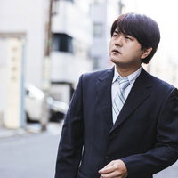 張り込みをするスーツ姿の探偵男性が街角で監視捜査の写真