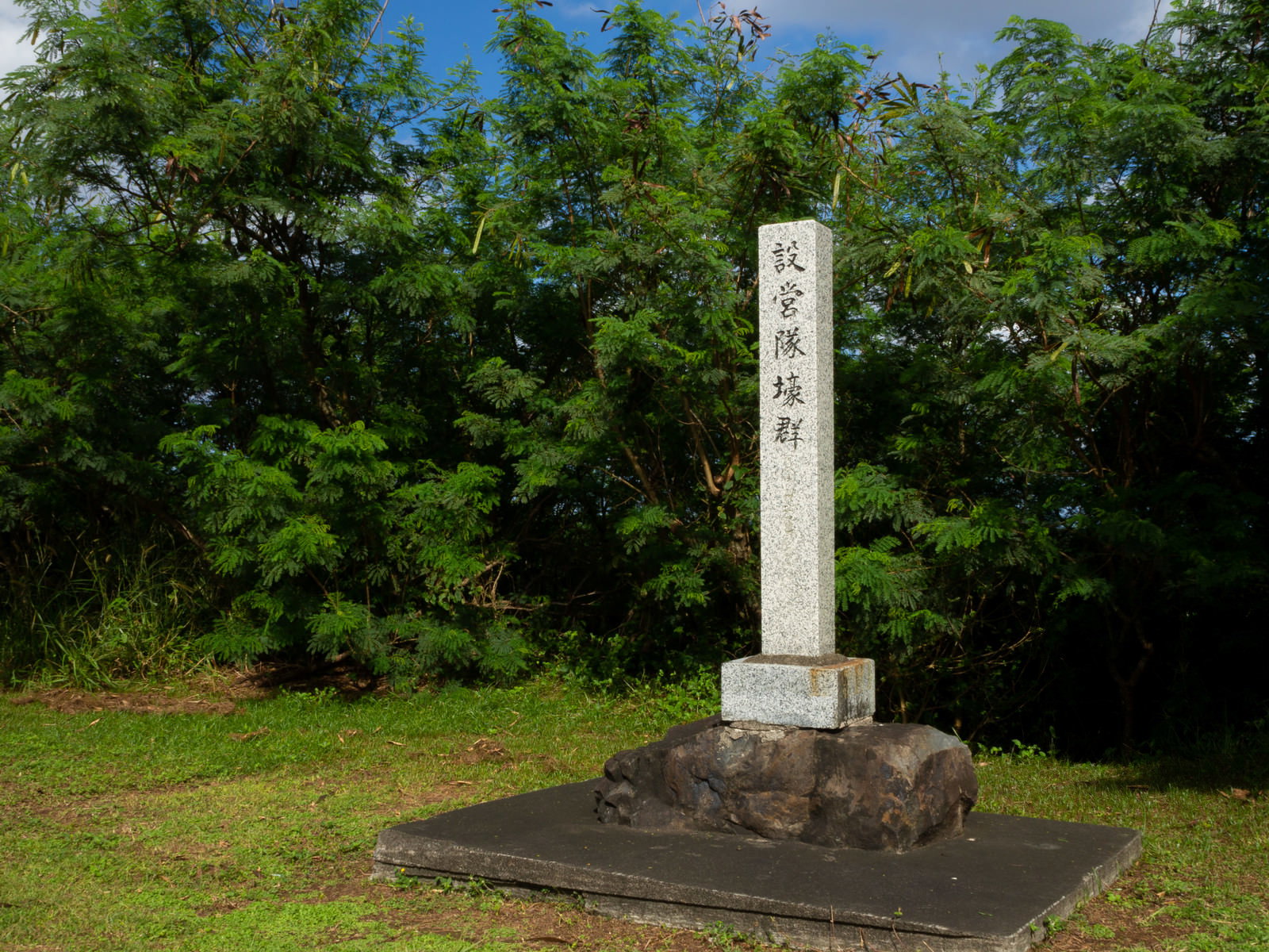 緑の木々に囲まれた場所に立つ海軍第204設営隊壕群の白い石柱の道標