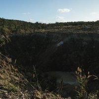 荒れ地にぽっかりと口を開けている硫黄島旧噴火口（ミリオンダラーホール）の写真