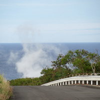 海へと続く道から見える鶯地獄から上がる蒸気の写真
