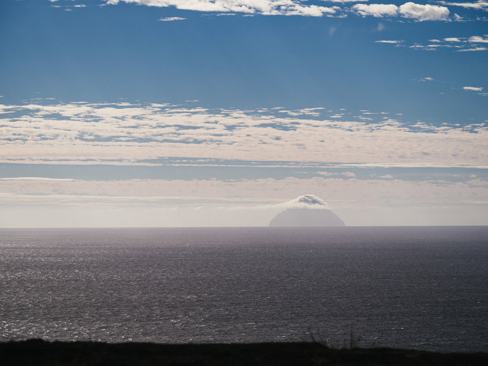 摺鉢山から望む雲に包まれた南硫黄島と水平線の風景