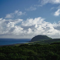霞んで見える摺鉢山と翁浜（上陸海岸）の写真