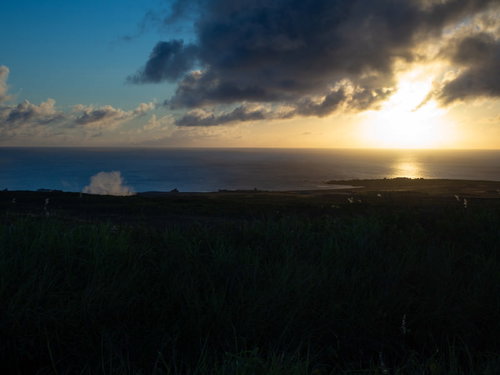 釜岩の向うに沈む太陽とシルエットとして浮かびあがる千鳥ヶ浜の沈船群とオレンジ色に染まる鶯地獄の蒸気