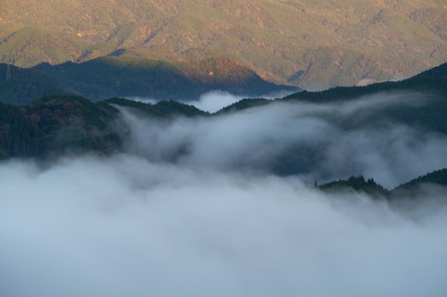 朝日に照らされ輝く山々と雲海に静かに沈む山々