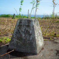 草木に覆われた硫黄島の米海軍標識とコンクリート遺構の写真