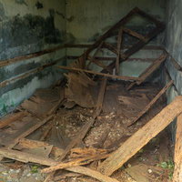 木片がバラバラと散らばるコンクリート建造物内部の写真