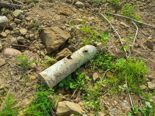 瓦礫や岩と共に地面に転がる砲弾薬莢