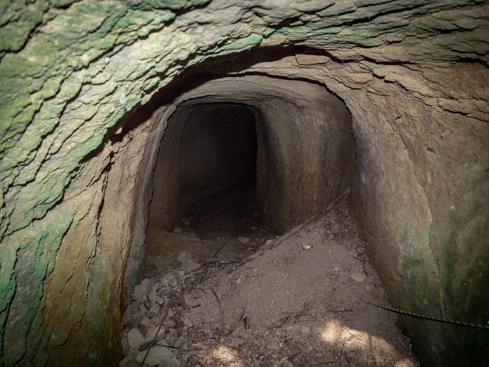 石積みの壁と天井で造られた地下壕の内部通路、奥は暗闇
