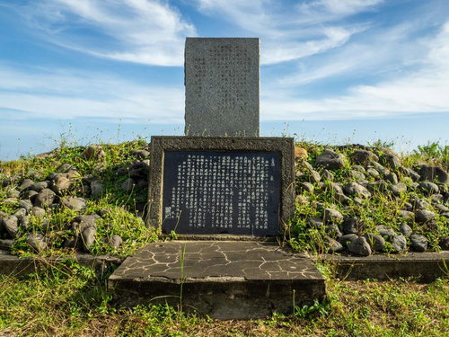 青空と雲の下に建つ日米再会の碑と石積み基台