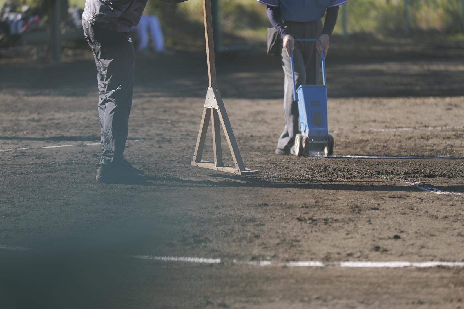 The groundskeeper is leveling the soil on the ground using a roller.