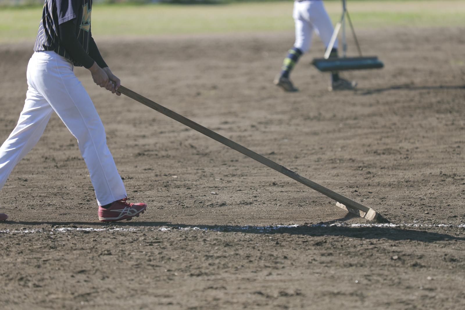 The person in a white work uniform using dragonflies to maintain the baseball field.