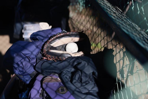 ダッグアウトベンチに置かれた紺色ユニフォームとキャッチャーミット