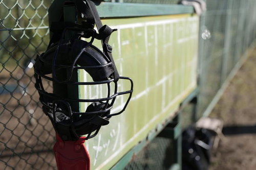 金網フェンスに掛けられた黒いキャッチャーマスク