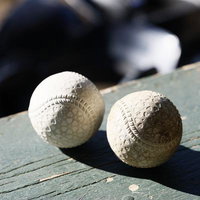 木製ベンチに並ぶ2個の野球ボール、赤い縫い目がくっきりの写真