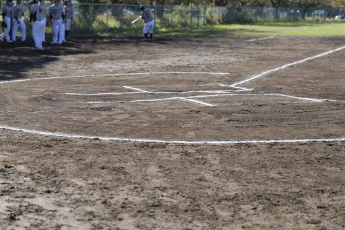 白線で区切られた野球場のホームベース周辺と土のグラウンド