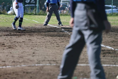 審判と選手が写る土のグラウンドでの野球の試合
