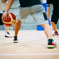 室内コートでドリブルするバスケットボール選手の写真