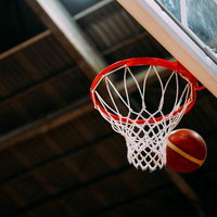 バスケットボールのリングを通るボールがシュート決定する瞬間の写真