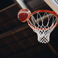 シュートしたバスケットボールがゴールのリングに向かうの写真